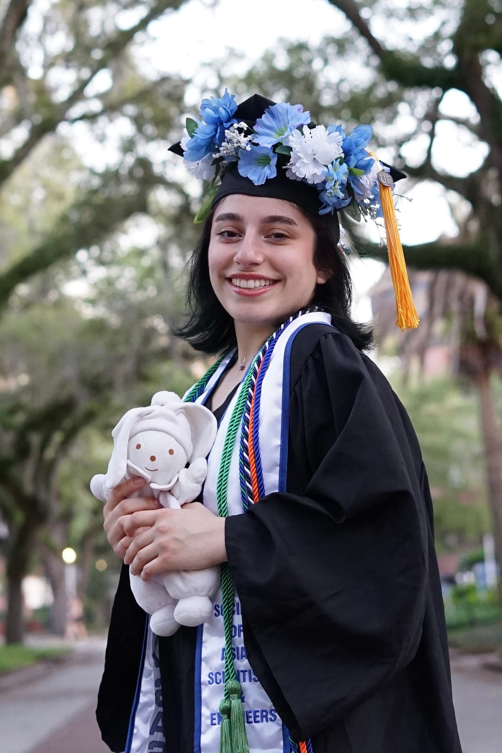 Francesca holding stuffed bunny rabbit in graduation regalia